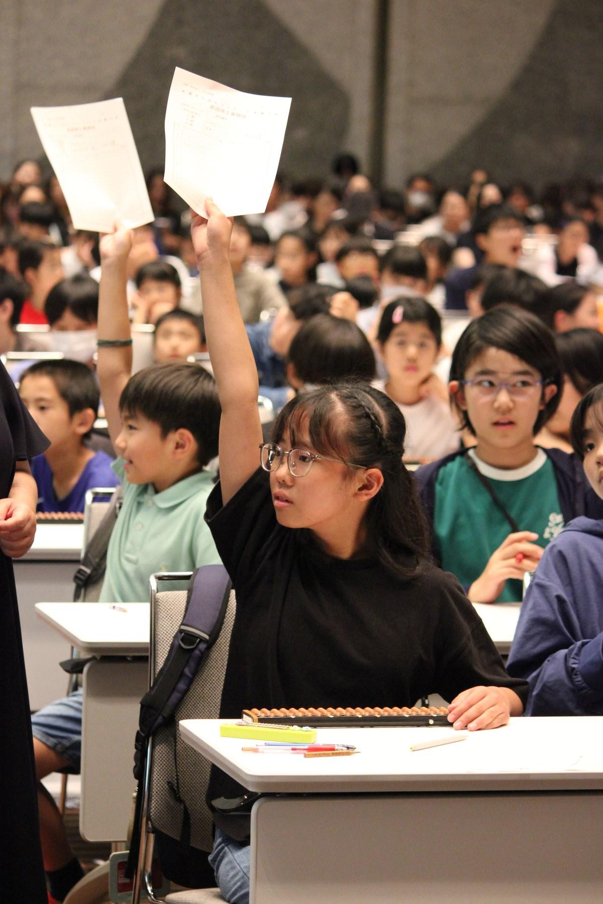 答えを書いた用紙を掲げる選手